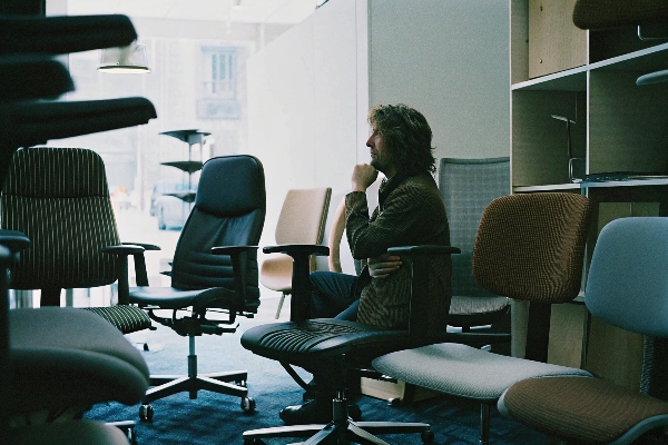 person thoughtfully considering different chair designs